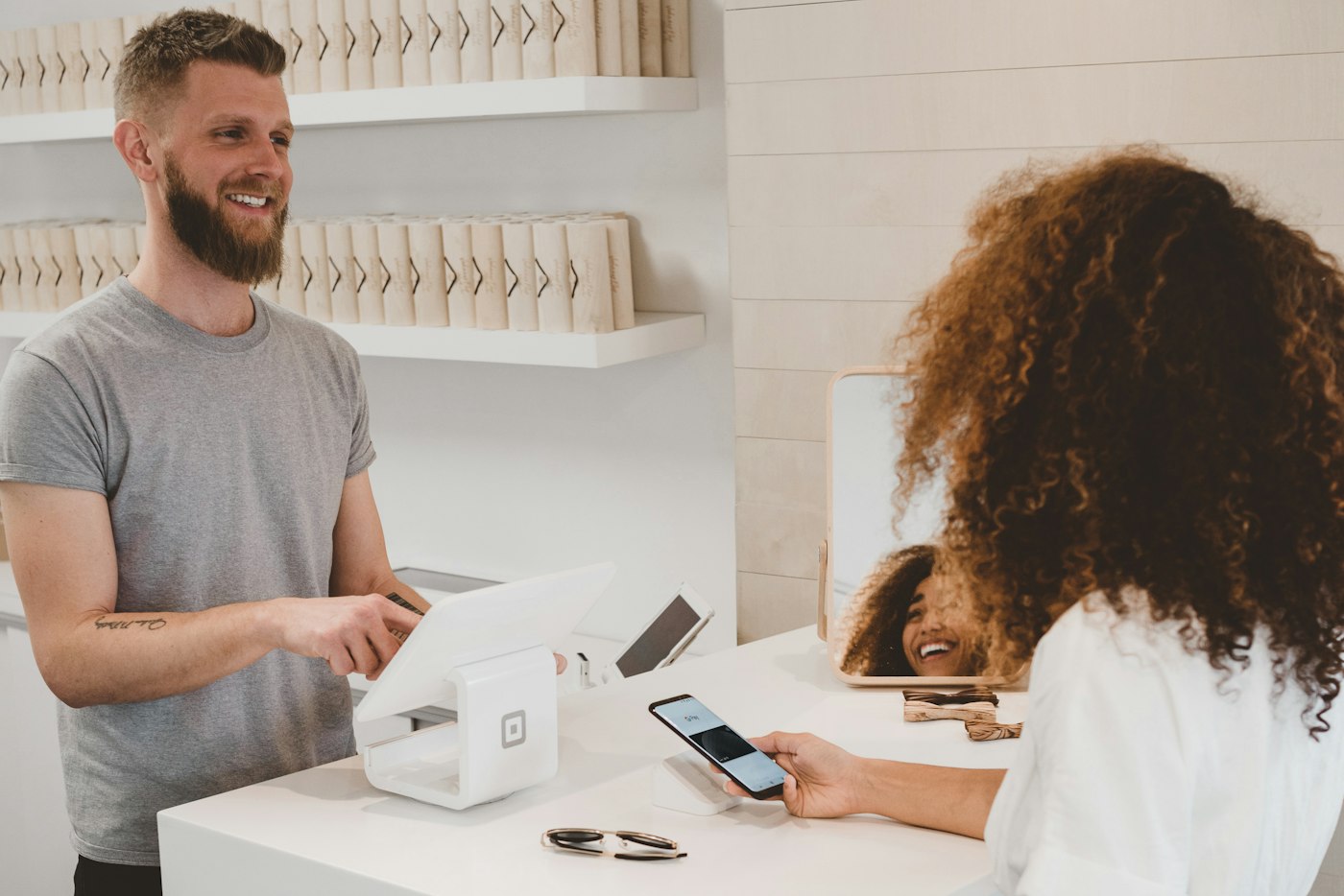 A shop employee smiling while helping a customer at the counter